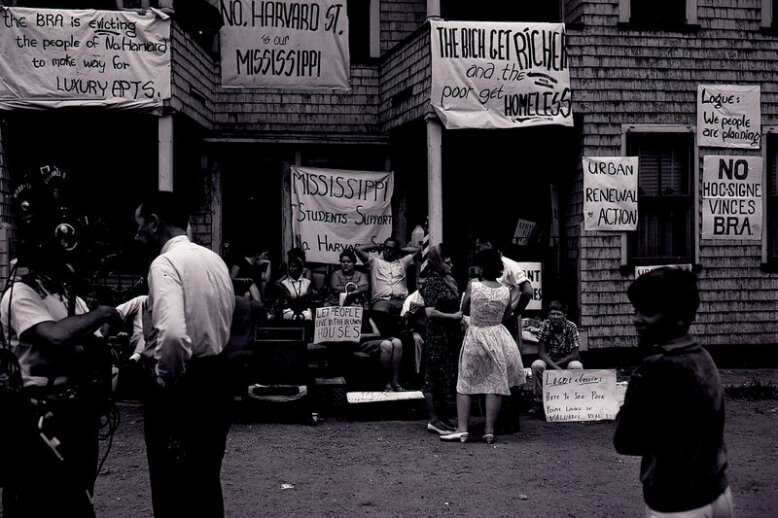 Building with protest signs People standing in front of a triple decker home decorated with protest signs.