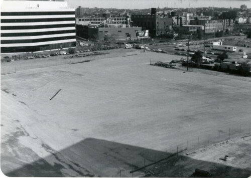 An empty lot with low rise office buildings on three sides.