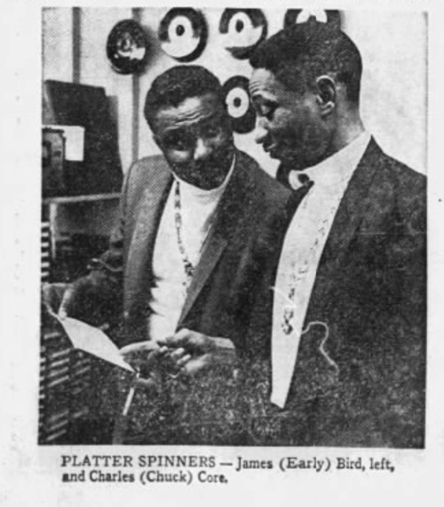 Two black men standing in front of records and radio equipment.