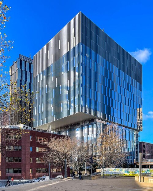 A modern glass office building at the corner of a street.
