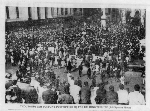 A large crowd of people at a tribute rally in a public square.