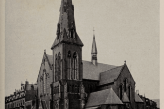A church building with a tall spire and a chapel coming off the side.