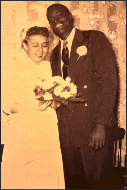 A man and woman in wedding clothes smiling for the camera.
