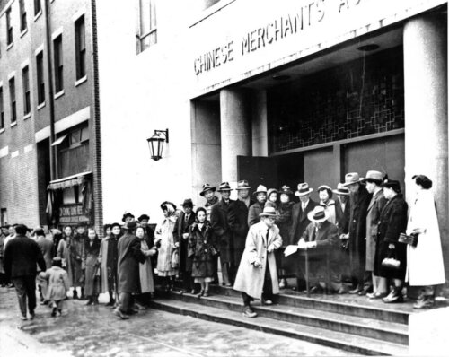 A group of Chinese-American protestors standing in front of a building.