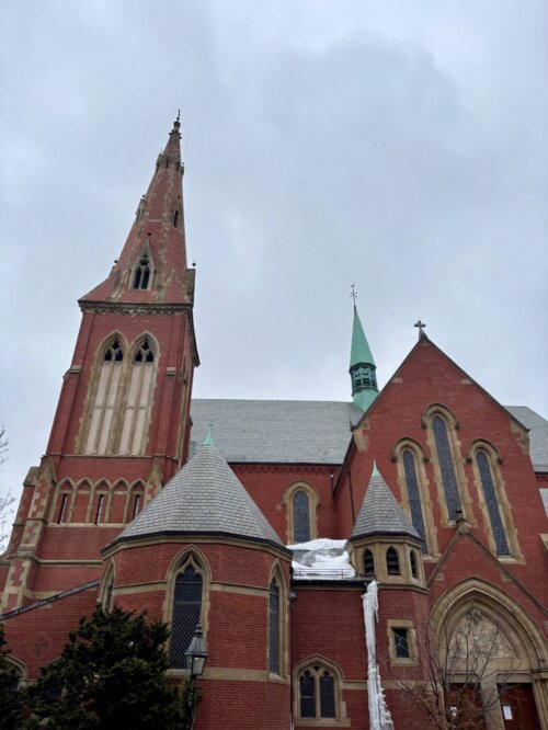 A church as seen from the side. The nave, spire, and side chapel can be seen.