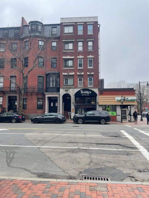 A five story brick building with a restaurant on the ground floor with the name "Teddy's on the Hill".