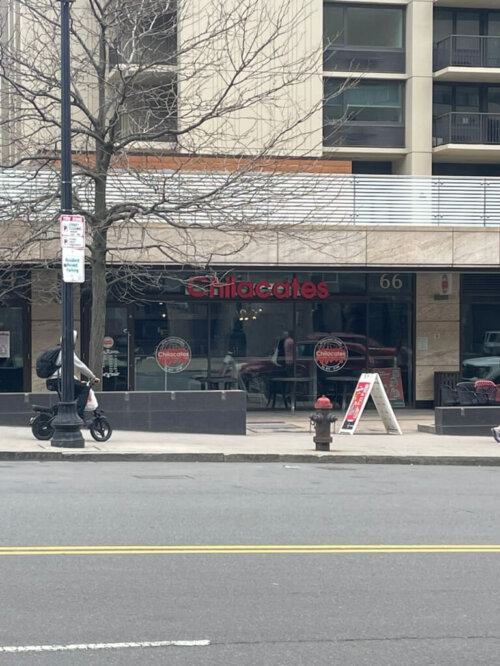 A storefront at the base of a tower apartment complex with the name of the restaurant in red "Chilacates".