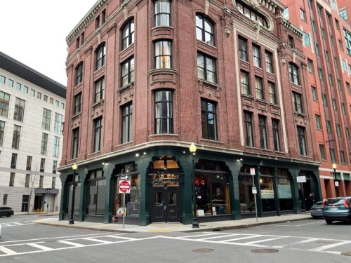 A brick building with a storefront on the first floor painted dark green.