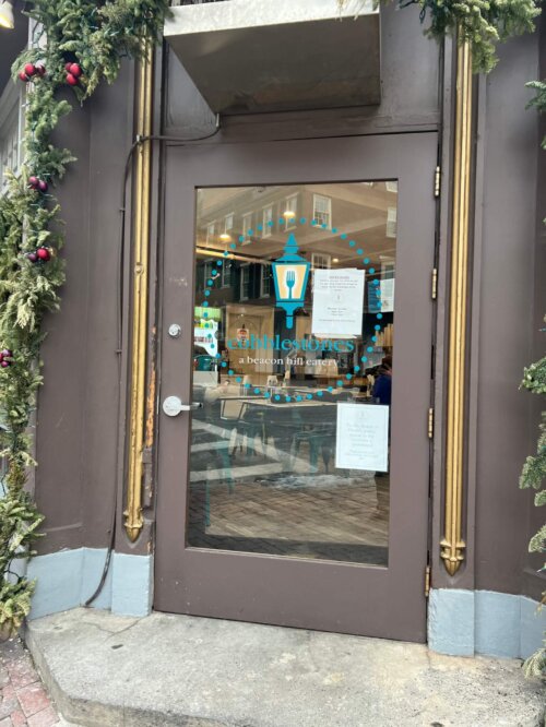 A brown trimmed glass door with an illustration of a lantern head on the glass over the words "cobblestones a beacon hill eatery."