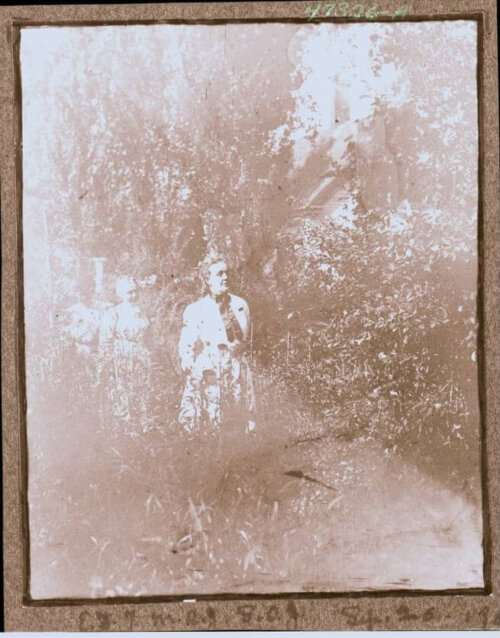 Three women stand in an overgrown garden. The photo is grainy and hard to see.