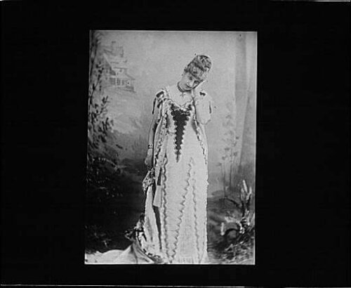 A photo of a woman in a fanciful dress with her head in her hand.