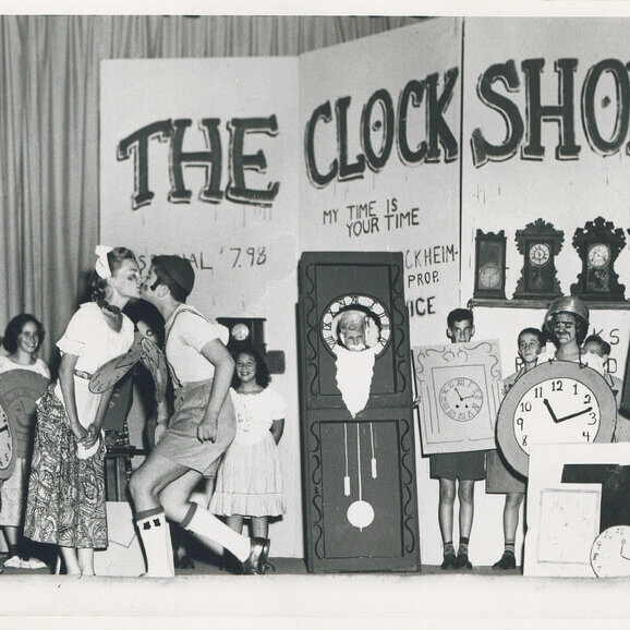 A group of children in homemade clock costumes performing in a play.