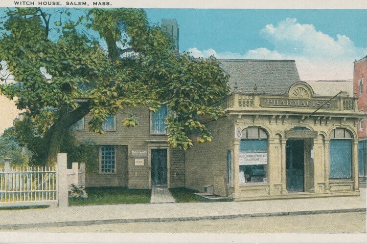 The Witch House (Salem Public Library) A postcard of a colonial house with a more modern storefront closer to the street. There is a large tree covering most of the hosue