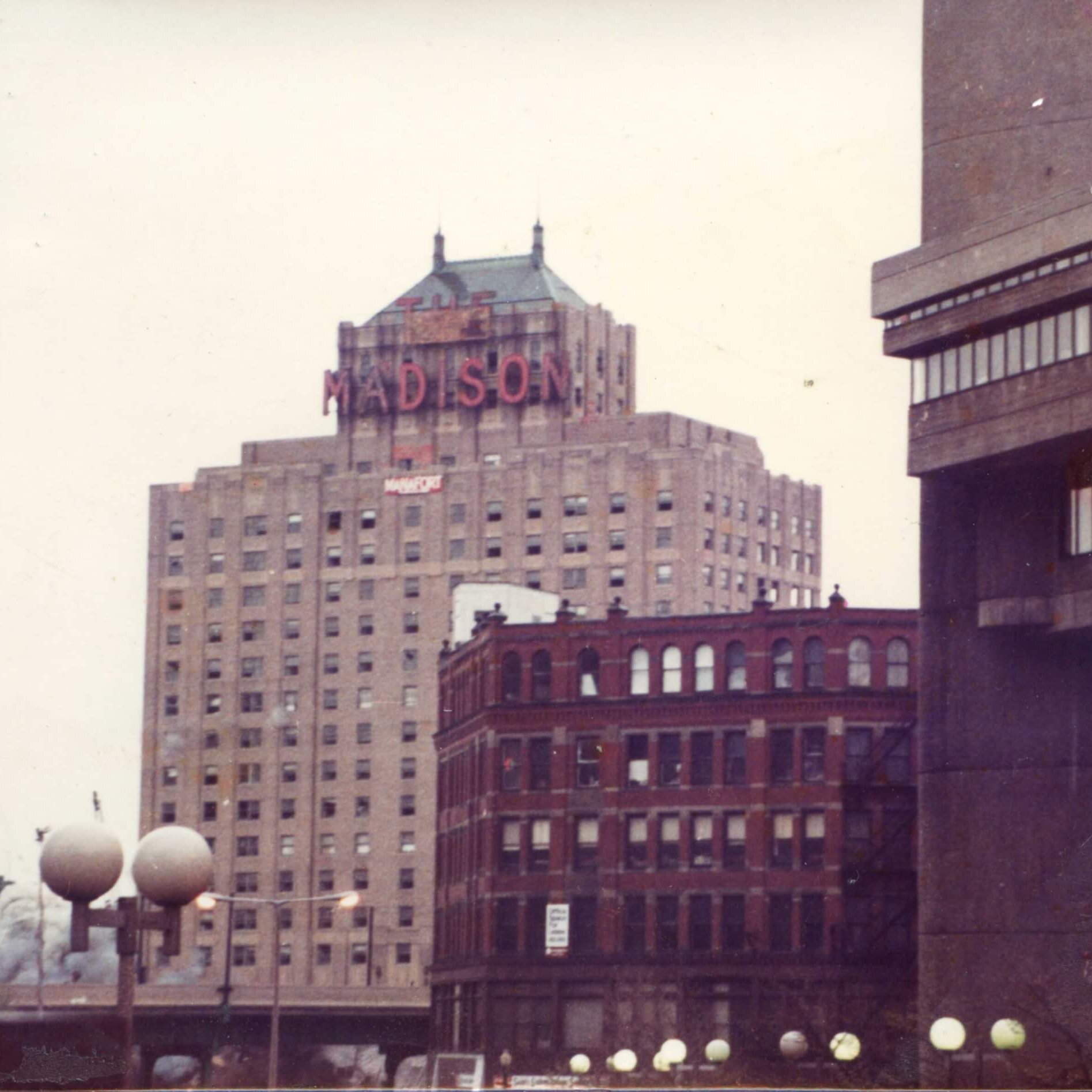 A tall hotel with the marquee that says Madison with a cloud of dust at the botto