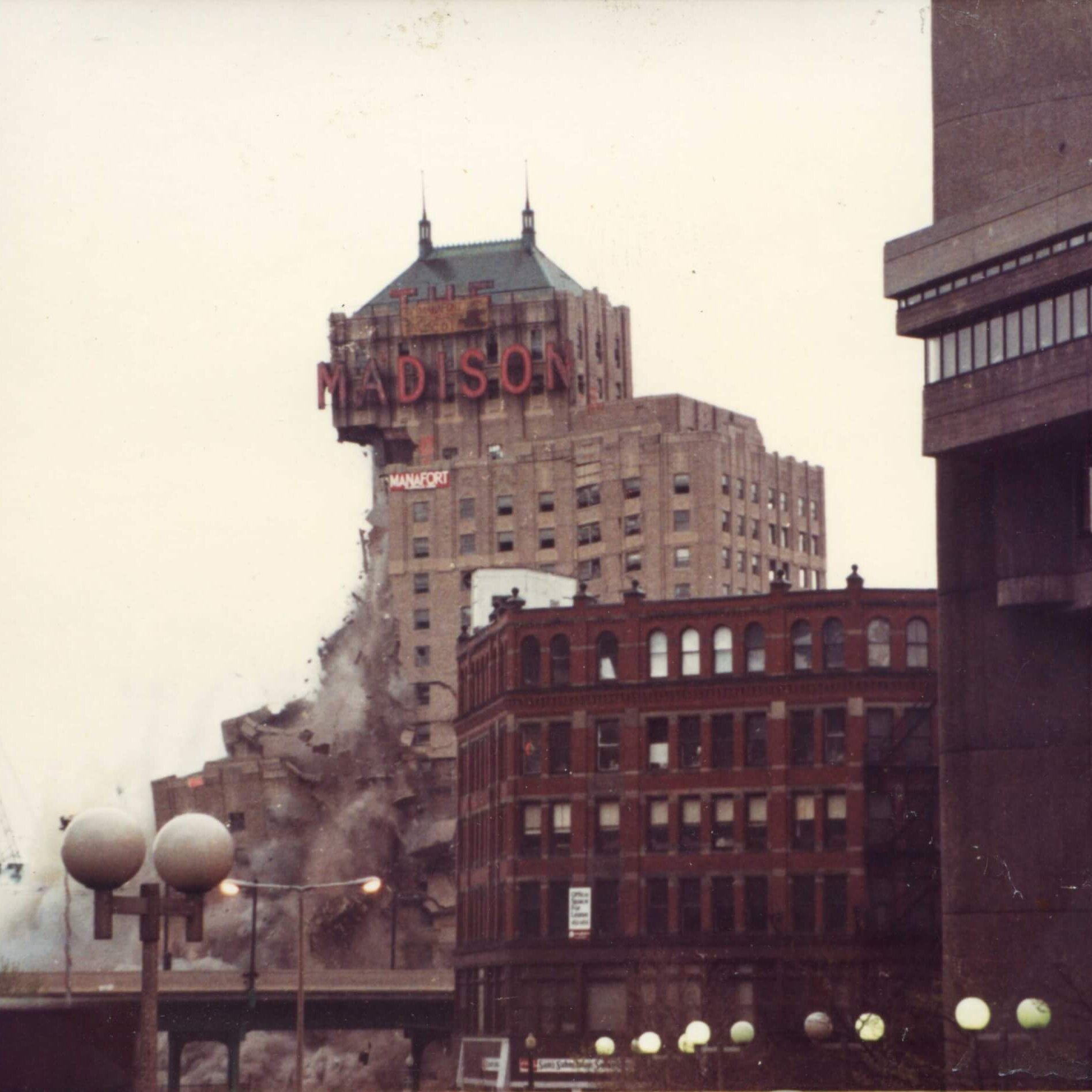 A tall hotel with the marquee that says Madison. The left side has collapsed into dust and rubble.