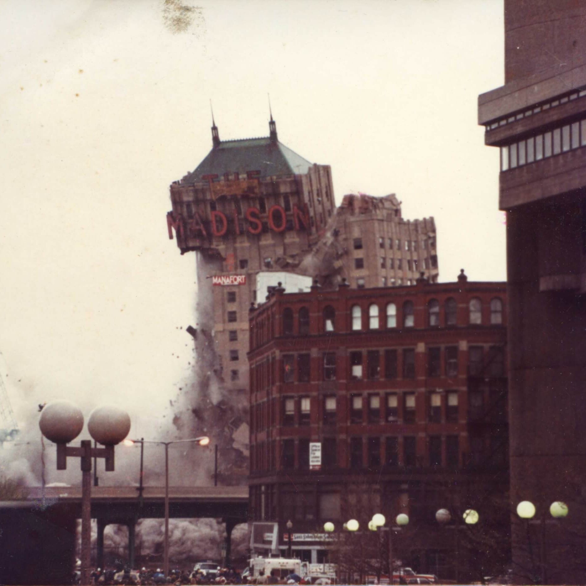 A tall hotel with the marquee that says Madison. The left side is gone and the marquee is tipping over.