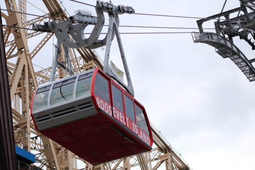 A view of a red tram car suspended on wires.