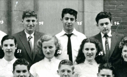 Three rows of teenagers posing for a class picture. The first and last row are boys and the middle row is girls.