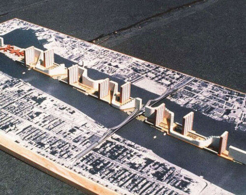 A photo of a model of a planned development on a long narrow island with several tall, narrow apartment buildings.