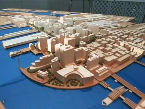 A small scale model of a neighborhood with tall buildings next to the water.