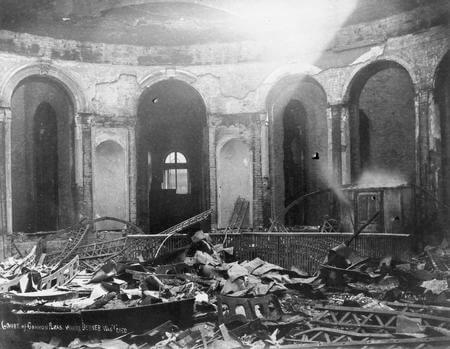 An image of the interior of a neo-classical style courthouse building with burned rubble on the floor.
