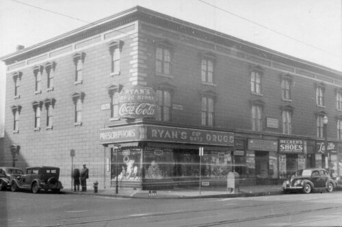 A three story building with a corner drug store in the far end.