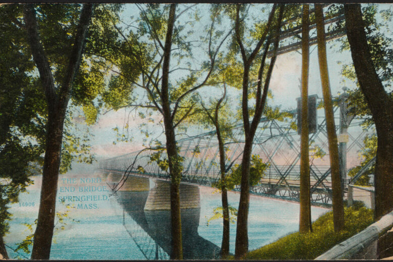 A colored photo of a railway bridge over a river with trees lining the river bank.