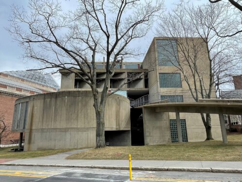 A concrete building with a rounded section on the left and a long ramp leading up from the right.