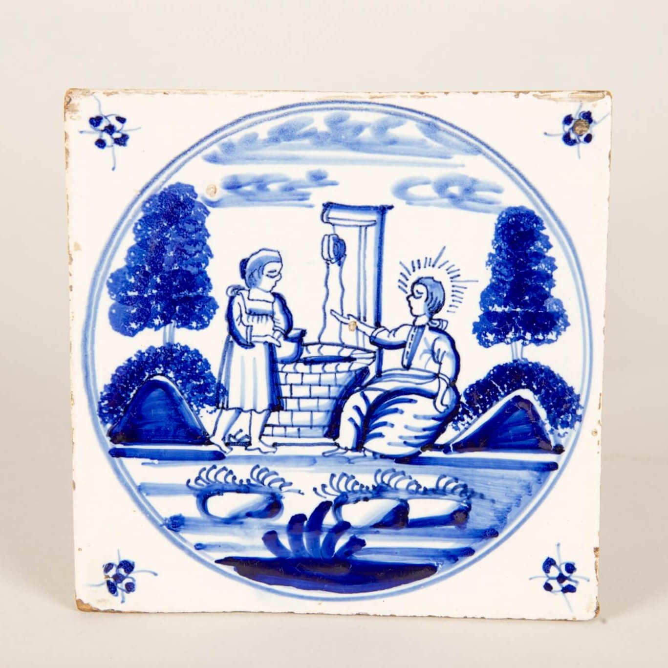 A blue and white tile showing a woman and man beside a well.