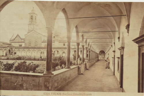 A sepia photo of a cloister interior. There are arches and walkways surrounding a central garden. There's a church in the background.