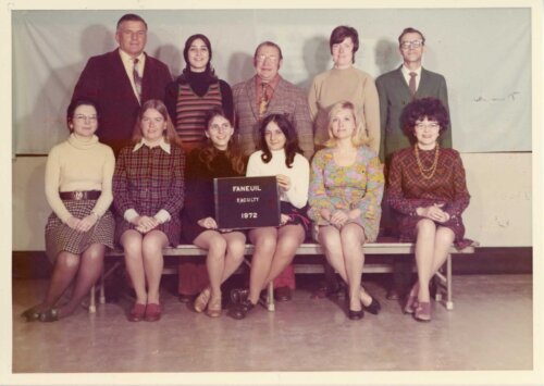 A group of men and women in 1970's clothing posing for a picture.