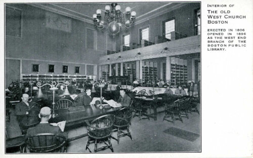 A black and white postcard showing a reading room in a library. There is a balcony above.