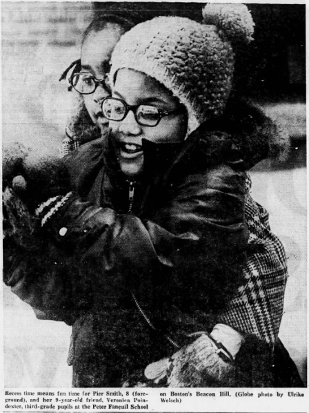 Two girls in winter coats, hats, and gloves play in the snow.