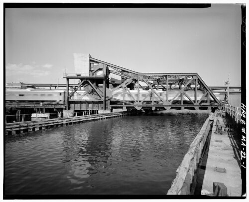 A motion-blur train crossing a low bridge over water.