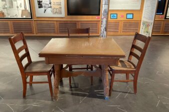 An image of a brown enamel top table surrounding by three chairs.