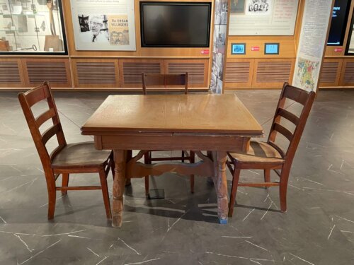 An image of a brown enamel top table surrounding by three chairs.