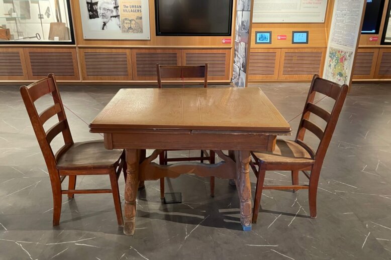 An image of a brown enamel top table surrounding by three chairs.