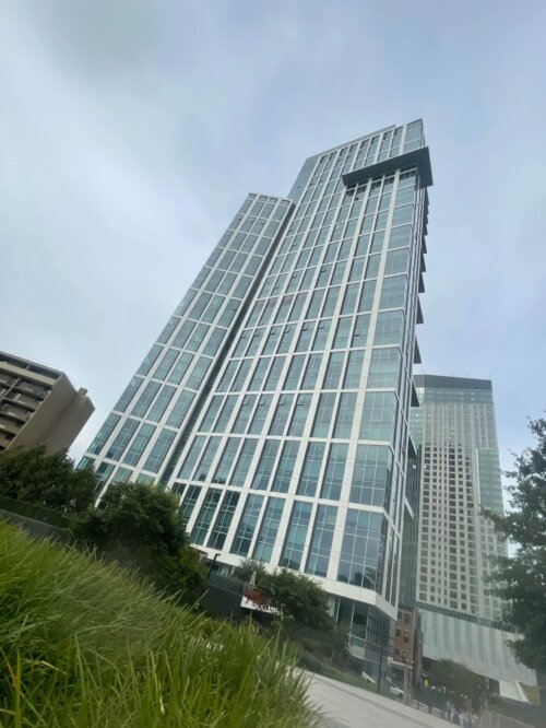 A dutch angle shot of a tall glass and steel apartment building with a blue tinge.