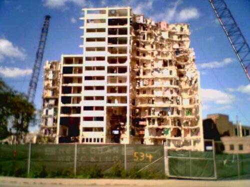 A high rise building in the middle of being torn down.