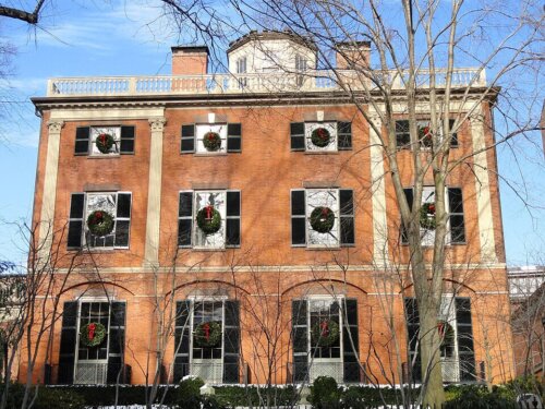 A three story brick building with wreaths in the windows.