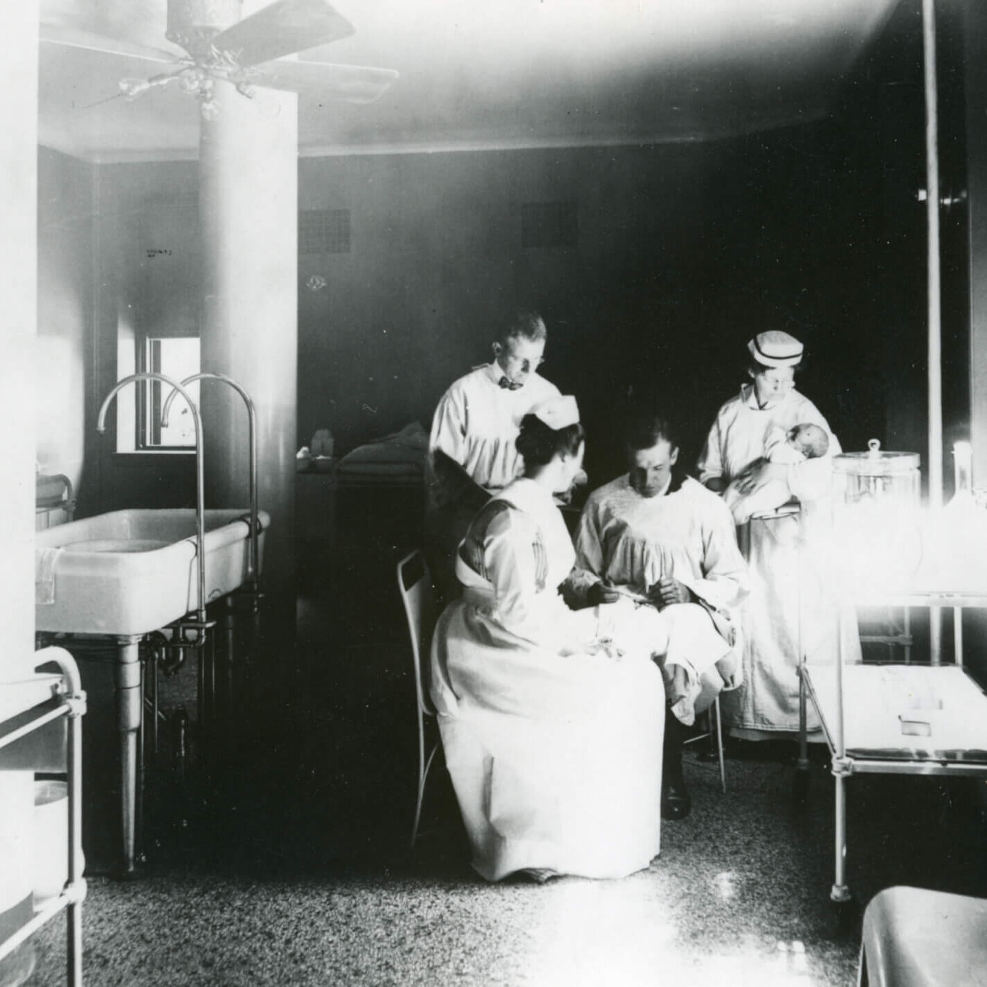 A hospital ward where two men and two women in medical clothing attend to children.