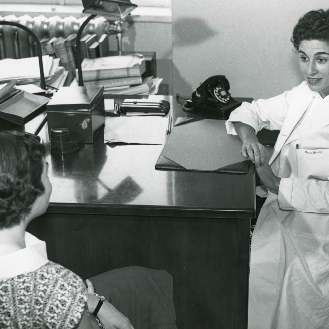 Two women sit across from each other at a desk.