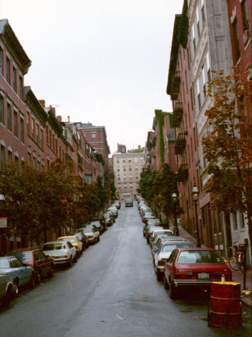 A photo looking up a street with cars on either side of the street.